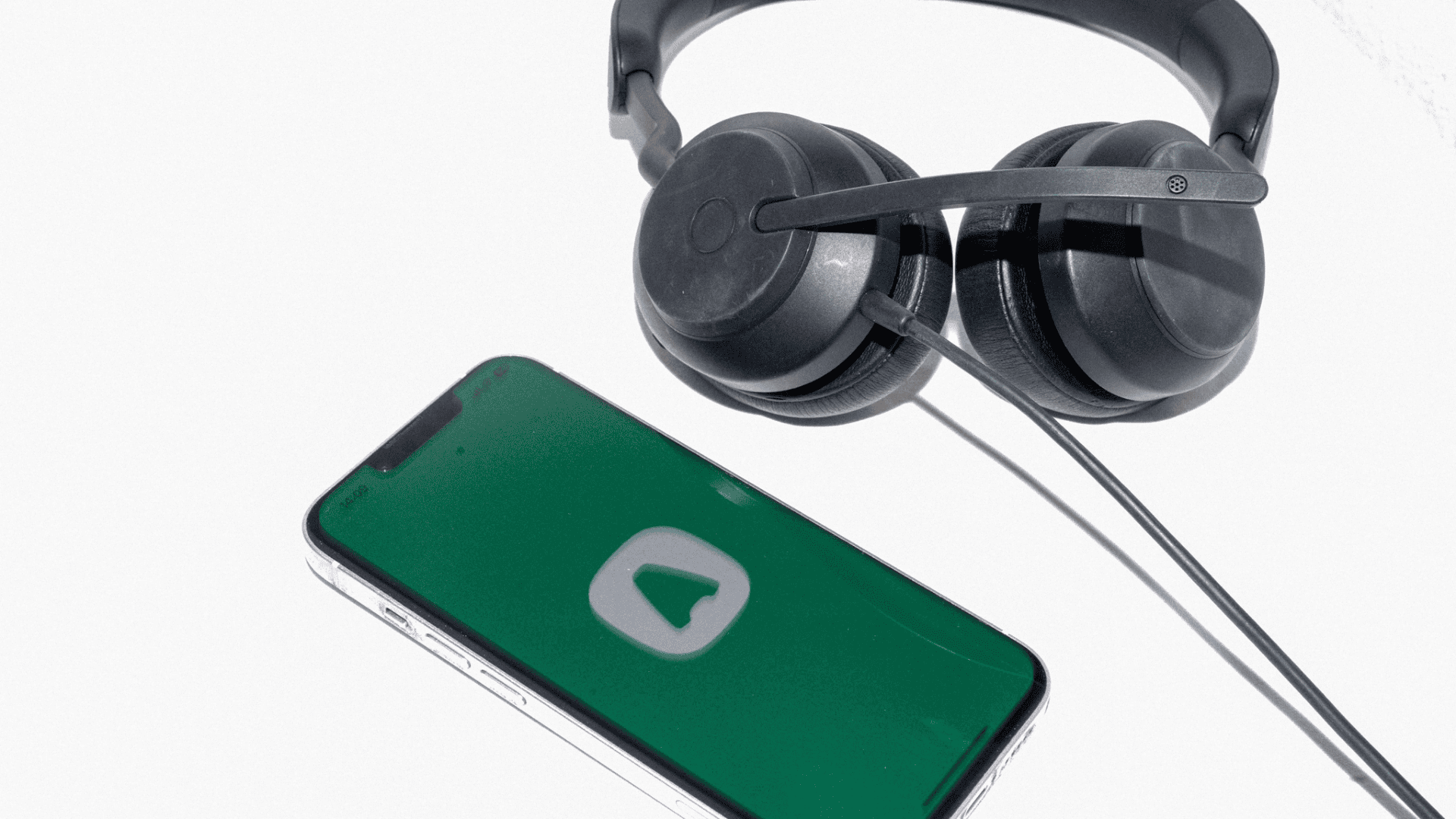 Black headphones next to smartphone displaying Aircall, a green app interface with white logo.