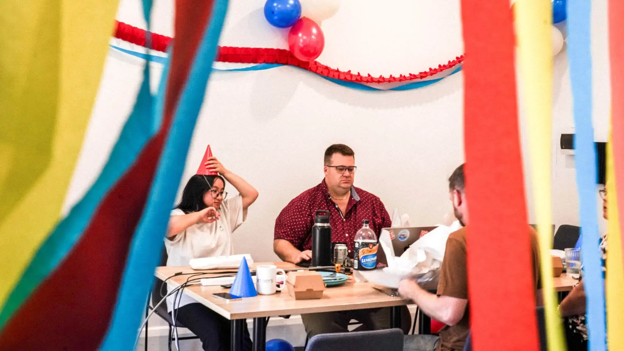 Three members of the Refuel team around a table with party decorations around the room