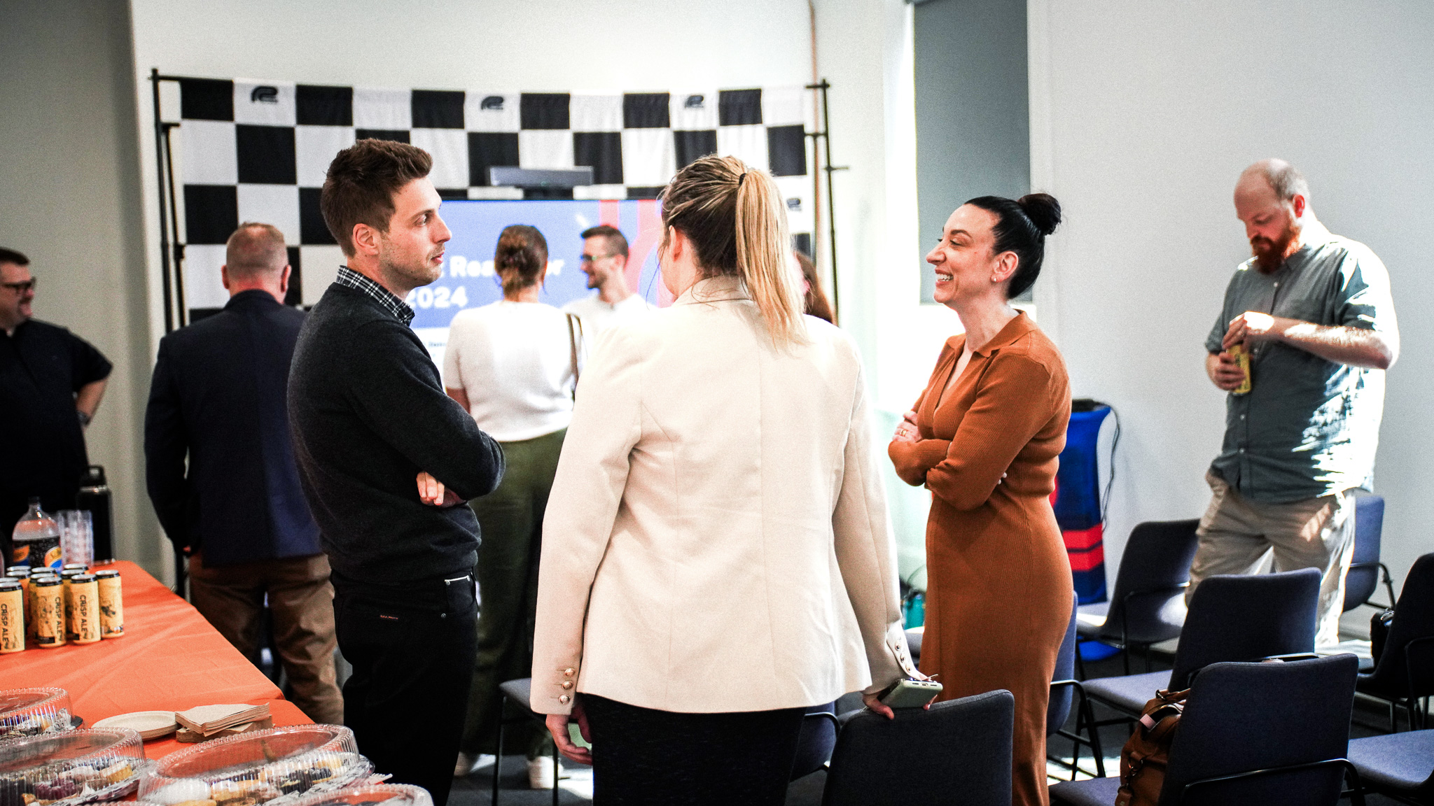Professional networking event with people conversing in modern office space with checkered wall art