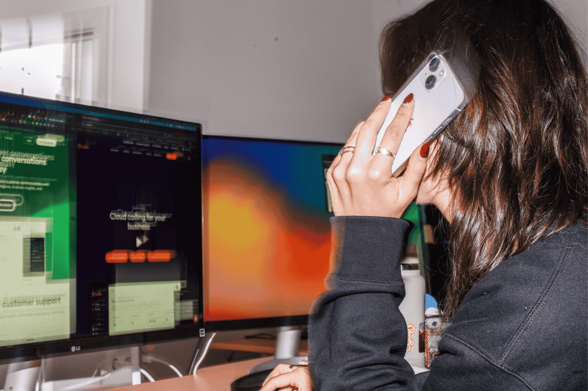 Person on a phone near monitors showing cloud calling business solutions.