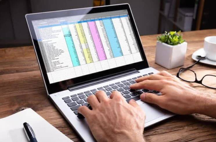 hands typing on laptop working on spreadsheets